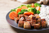close up of plate of fried tofu, rice and vegetables with sesame seeds