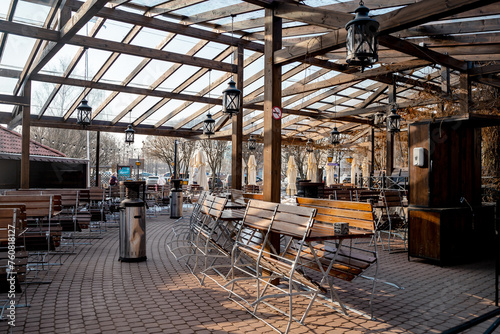 A restaurant with an outdoor terrace on the street with wooden furniture, the restaurant has not opened, chairs and tables are stacked. Saint Petersburg, Russia - 16 March 2024