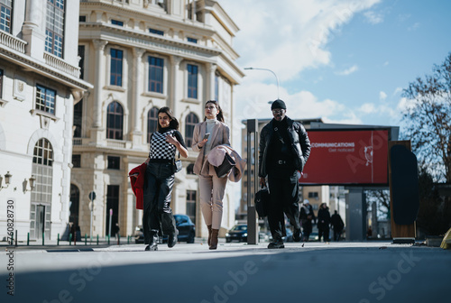 Three young business associates stride with confidence along a city street, showcasing modern professionalism and partnership.