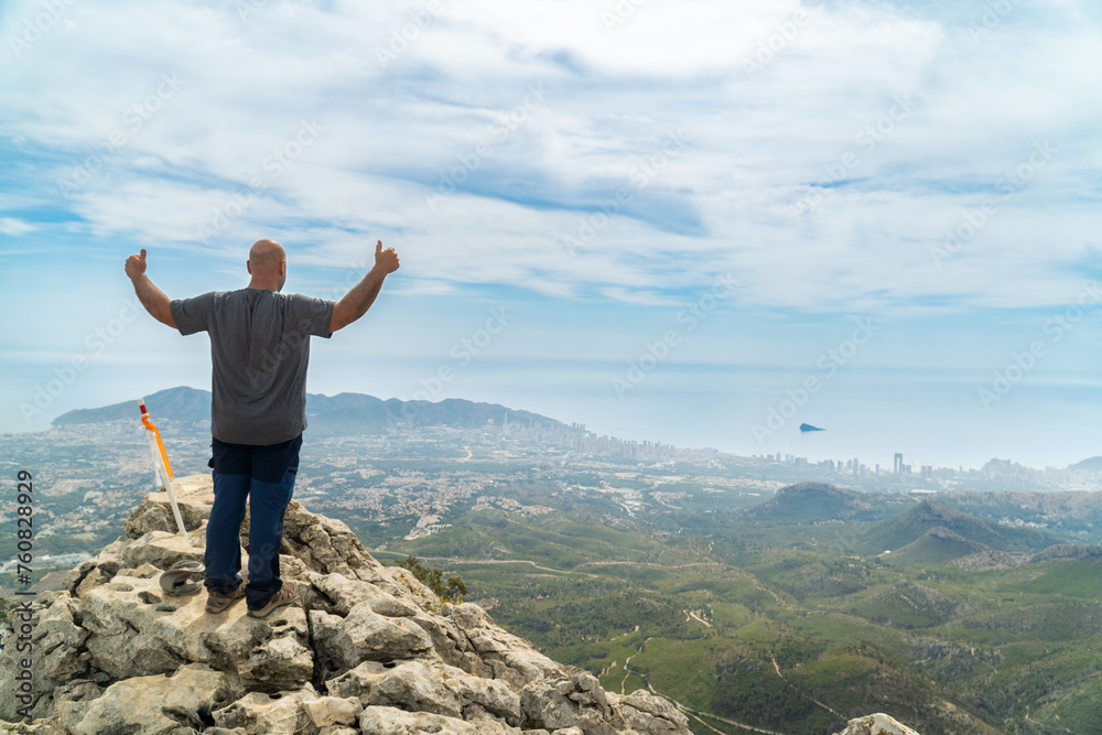 Back view. Mountaineer on top of the mountain with thumbs up. Back view. Mountaineer on top of the mountain with thumbs up.