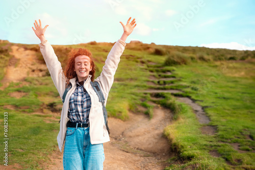 amazing redhead woman raising her hands, reaching the destination. Enjoy hiking and exploring new places concept