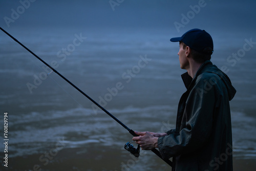 Man fishing on the mountain river at evening