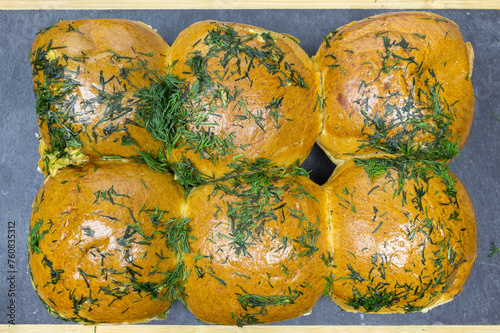 Rich, fluffy fresh buns with garlic and dill on a black kitchen board. Closeup. Top view photo