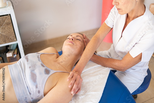 Osteopath stretching neck of client during treatment