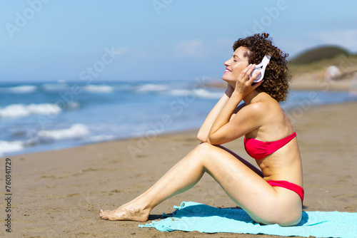 Happy woman listening to music on sandy beach