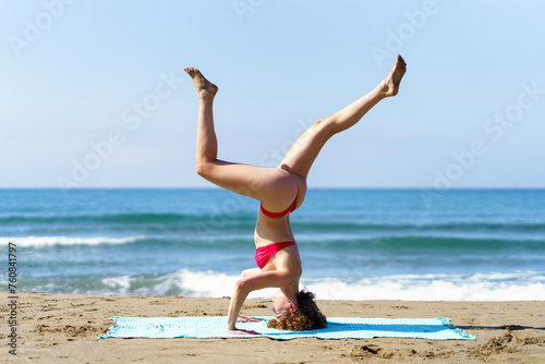Slim lady performing yoga on coastline