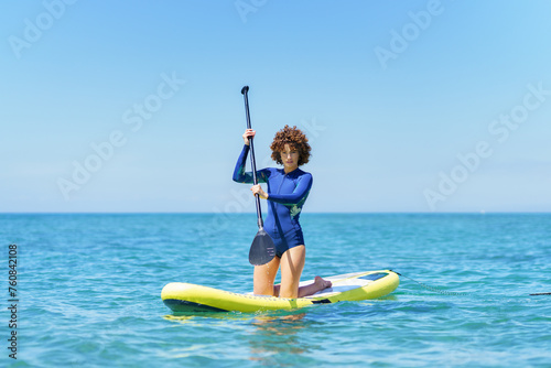 Confident woman on paddleboard in sea