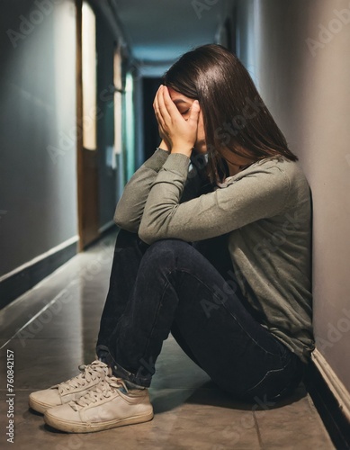 Sad Young Woman Sitting on the Floor In the Hallway of Her Appartment, Covering Face with Hands