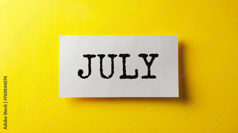JULY written on a white sheet of paper on a yellow background