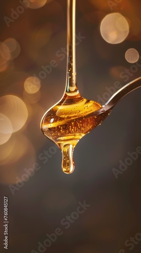 a spoon full of liquid with a drop of liquid hanging from it's side and a blurry background. photo