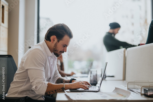 Concentrated male person in a white shirt works diligently on a laptop in a well-lit contemporary office setting, embodying productivity.