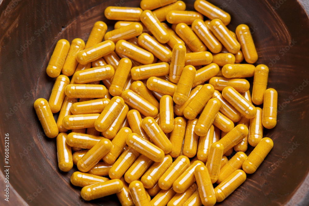 Turmeric capsules in wooden bowl. Herbal supplement organic curcumin pills. Medicinal ingredient Turmeric capsules in wooden bowl. Herbal supplement organic curcumin pills. Medicinal ingredient