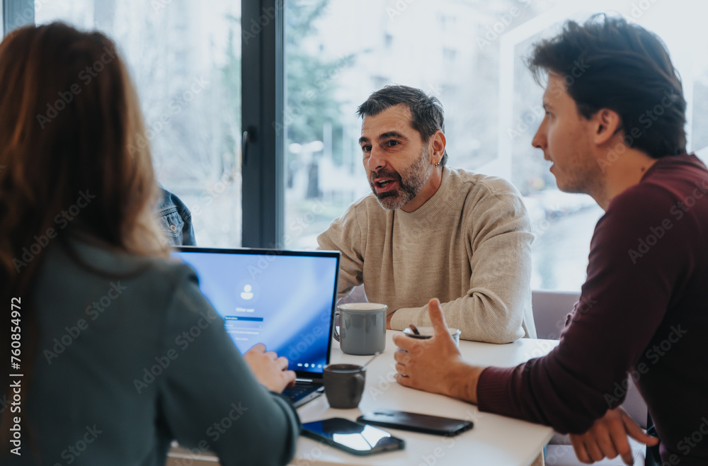 Fototapeta premium Multi generational colleagues collaborating in a positive meeting room. Creative brainstorming and sharing of ideas create a successful workplace.