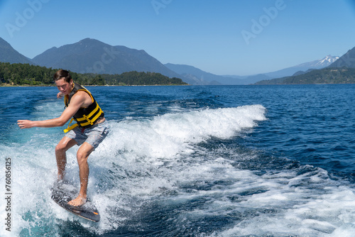 Young man enjoying wake surfing on the lake on a beautiful summer day in southern Chile.