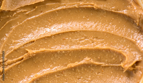 Peanut butter texture swirls background. Creamy smooth peanut butter backdrop, organic food. American cuisine. Top view