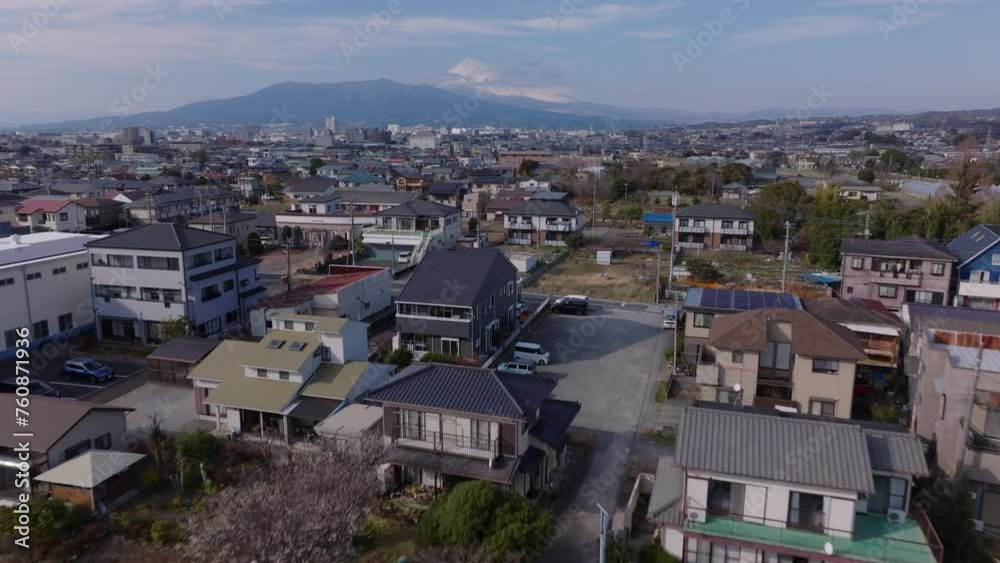 Fly above family houses in residential urban borough. Town in flat landscape. Majestic Mount Fuji with snowcap in distance. Japan Fly above family houses in residential urban borough. Town in flat landscape. Majestic Mount Fuji with snowcap in distance. Japan