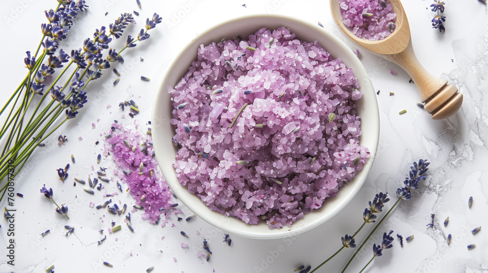 A top-down view of a bowl of homemade lavender scrub with scattered lavender flowers and a wooden honey dipper on a white background. A top-down view of a bowl of homemade lavender scrub with scattered lavender flowers and a wooden honey dipper on a white background.