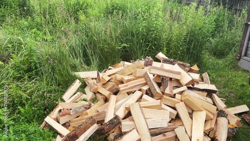 Firewood falls into a pile. Someone drops firewood into pile. Firewood pile on the grass at the backyard