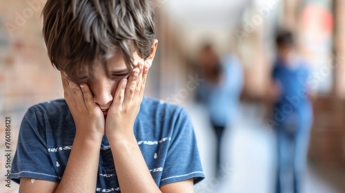 Teenage boy crying in school corridor, blurred background, copy space, learning difficulties concept