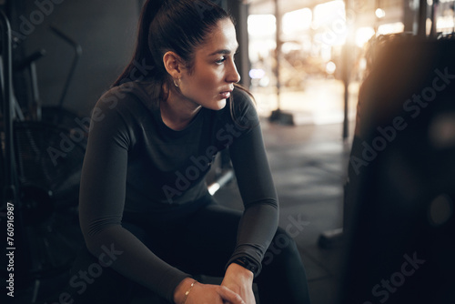 Fit young woman in sportswear taking a break from a rowing machine exercise session during a workout in a health club photo