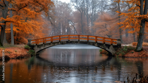 The autumn park with a bridge, surrounded by trees, whose leaves take various shades of yellow, orange and