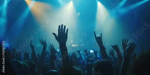 A crowd of people are at a rock concert, with their hands raised in the air