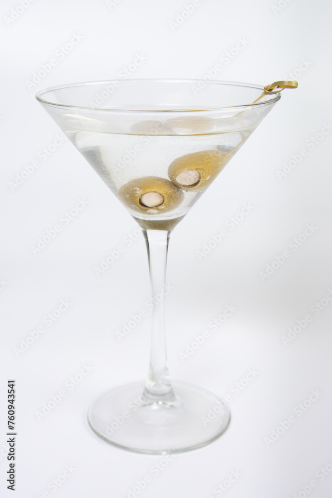 A martini glass filled with olive oil and olives