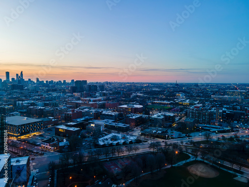 A captivating aerial view of a cityscape at dusk  showcasing illuminated skyscrapers against the darkening sky. The golden hues of sunset paint a serene backdrop  highlighting architectural marvels