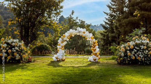 une arche de ballons blancs et dorés installée dans un parc pour un mariage, anniversaire ou une réception photo