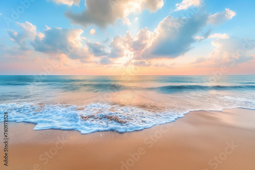 Sunrise over the sea, casting a soft glow on the waves and sand, with clouds scattered across the sky.