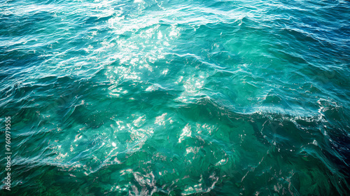 Glistening sunlight dances on the vibrant teal ocean waves, capturing the dynamic essence of the sea.