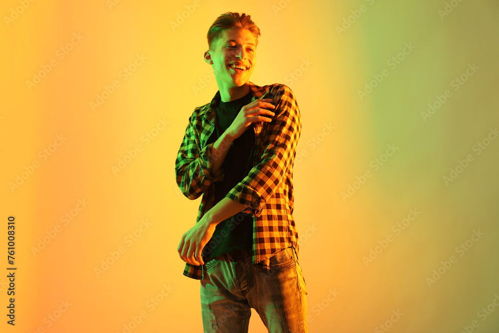 Young man dancing on color background in neon lights Young man dancing on color background in neon lights