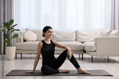 Beautiful girl sitting on yoga mat at home