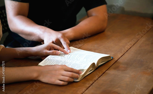 Woman and man read the Bible and hands point to Bible verses.
