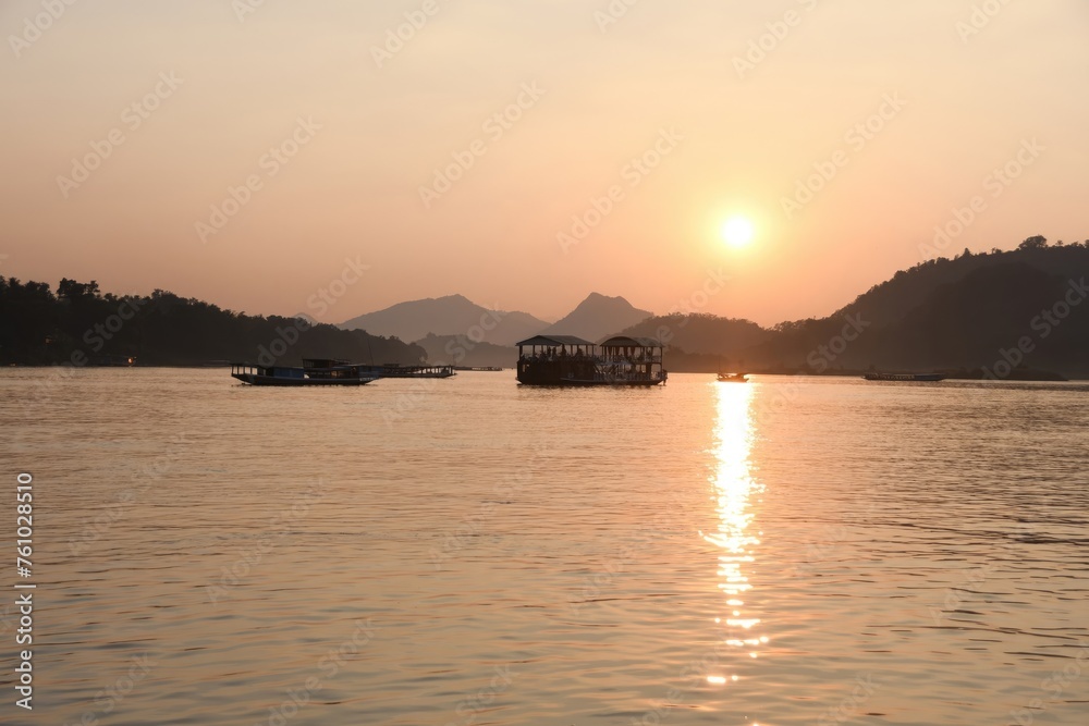 Naklejka premium Red and orange sunset paints the sky over a calm river reflecting the colorful light