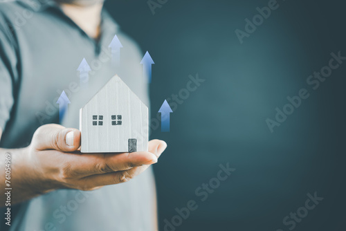 Increased value of real estate or property house concept. Real estate investment marketing analysis. Man holding home with icon grown up of income property value, earning profit investor strategy.
