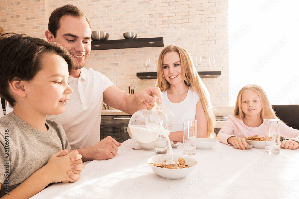 Happy family sitting at the table and eating breakfast