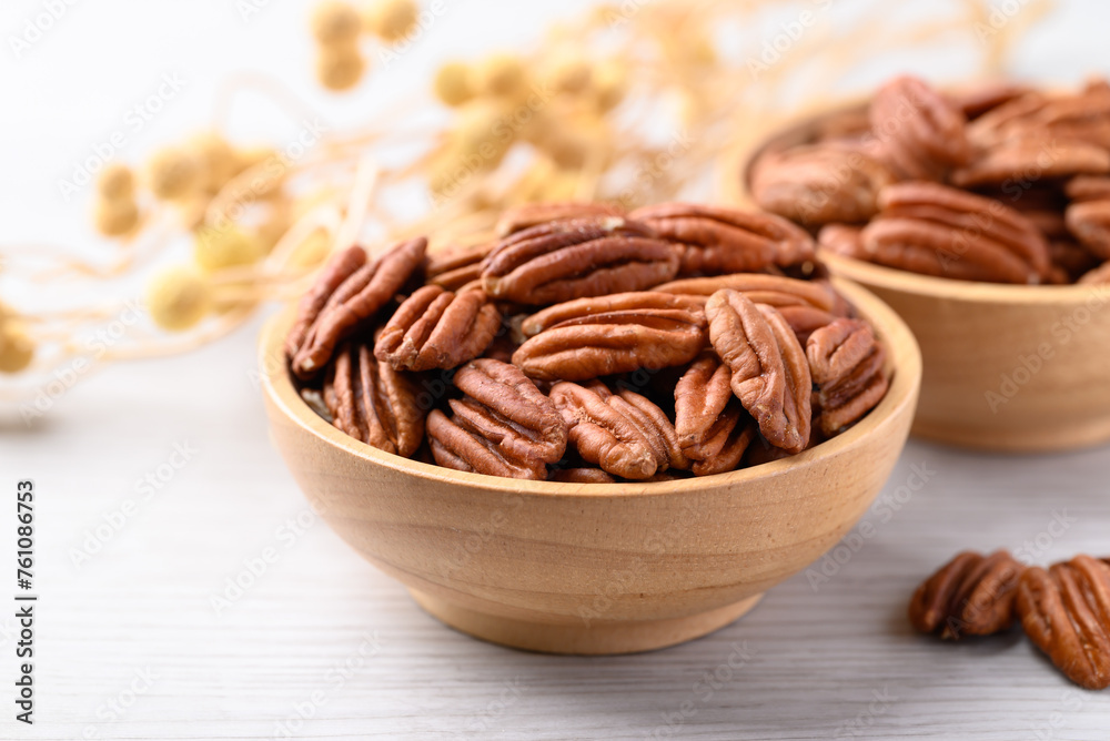 Raw peeled pecan nuts in wooden bowl on white table, Food ingredient Raw peeled pecan nuts in wooden bowl on white table, Food ingredient
