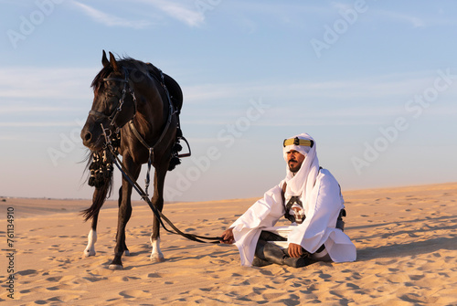 Saudi man in a desert with his black stallion photo