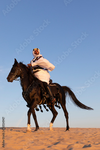 Saudi man in a desert with his black stallion © katiekk2