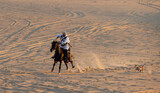 Saudi man in traditional clothing in a desert riding his horse