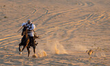 Saudi man in traditional clothing in a desert riding his horse