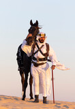 Saudi man in a desert with his horse