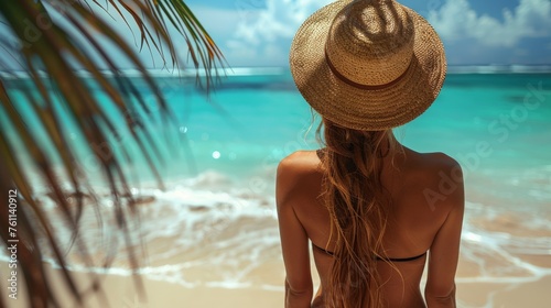 young blonde woman sitting at the beach overlooking the ocean - back view - travel concept © Salander Studio