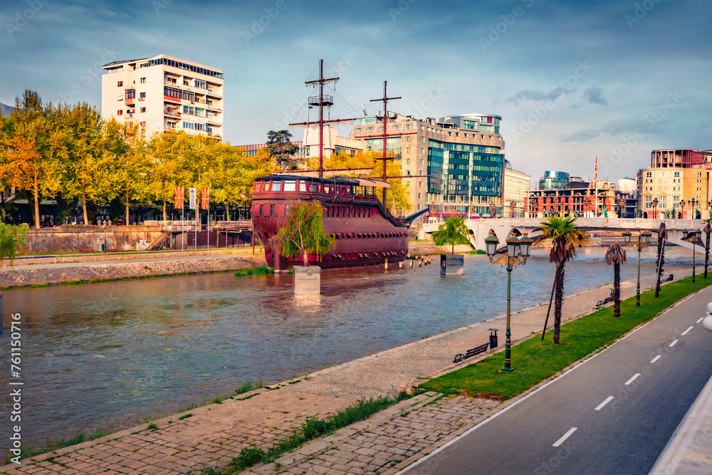 Spectacular spring cityscape of capital of North Macedonia - Skopje with old wooden sailboat and empty street at early morning. Traveling concept background. - obrazy, fototapety, plakaty 