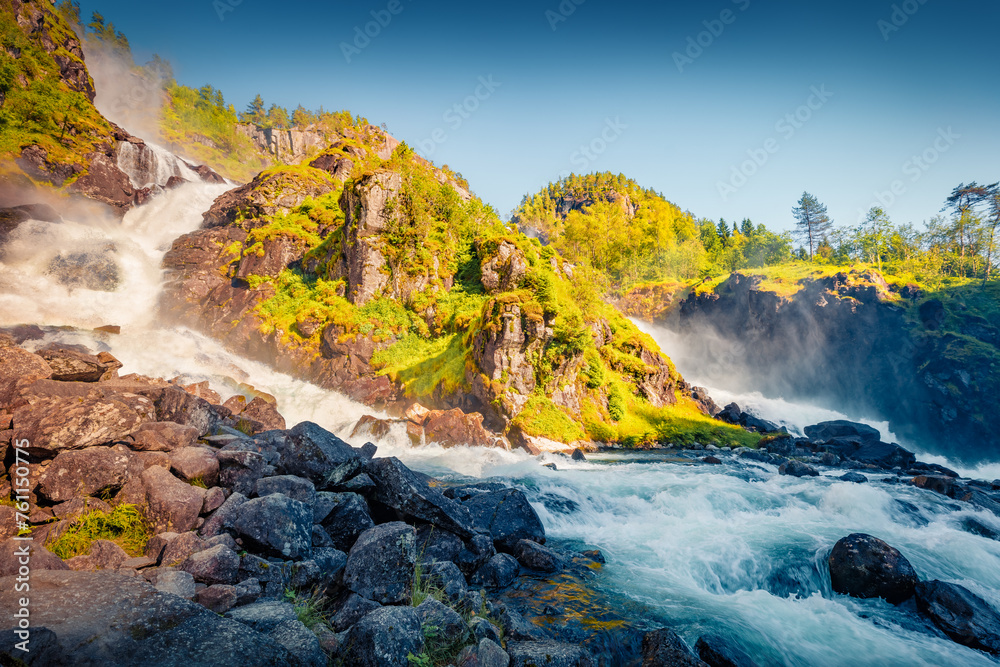 Majestic sunny view of Latefoss waterfall, located in the municipality of Odda in Hordaland County. Extraordinary summer scene in Norway, Europe. Beauty of nature concept background.