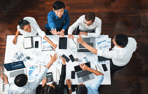 Top view diverse office worker join hand together in office room symbolize business synergy and strong productive teamwork in workplace. Cooperation and unity between business employee. Prudent