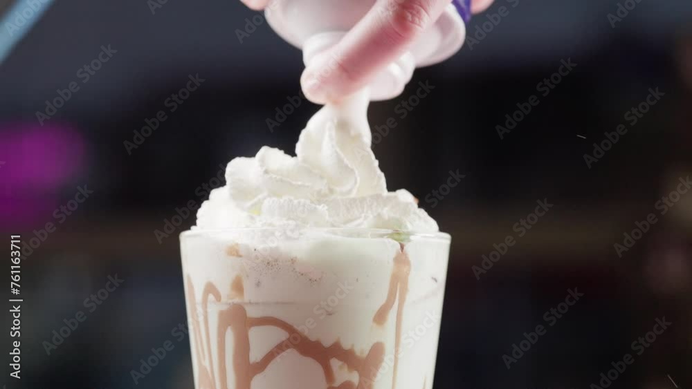 Spraying whipped cream over a chocolate milkshake