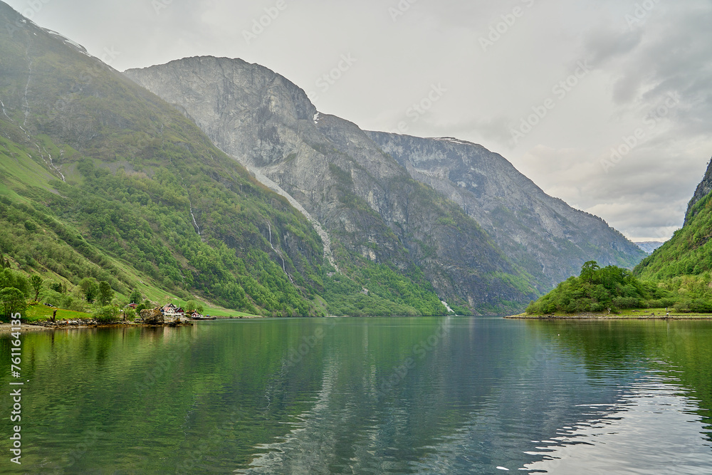 beautiful and tranquil landscape at the Naeroyfjord in Norway with snow covered mountains in the background.