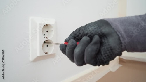 Man removing a plastic cover plate from a wall outlet